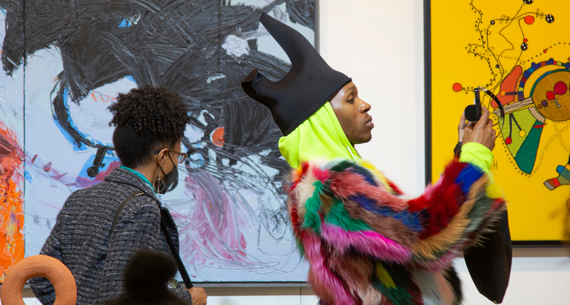 two people look closely at paintings at Art Fair 14C