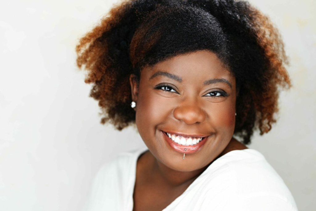 ARTS 14C Special Project artist Asia E. Marché smiling in a close-up portrait against a soft white background.