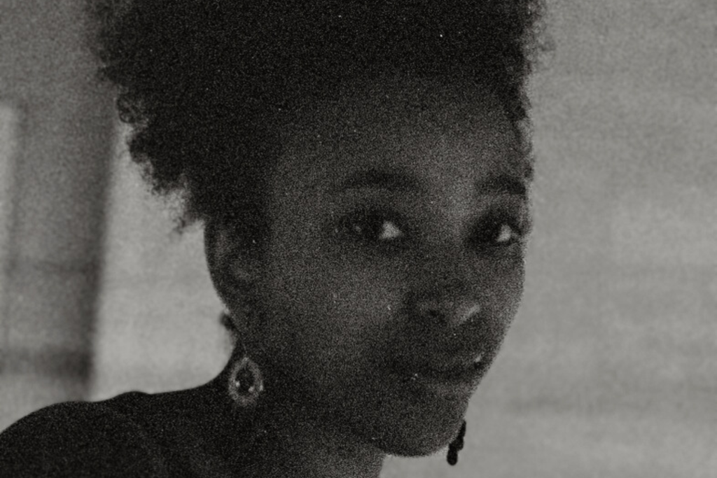 Black-and-white close-up portrait of ARTS 14C Special Project Artist Danae Venson, looking to the side with her hair pulled up and wearing dangling earrings.