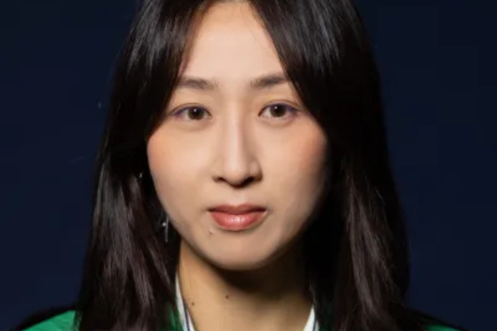 Headshot of ARTS 14C Fellowship Artist Jackie Yunchang Zhang, with long dark hair, looking directly at the camera against a dark blue background.
